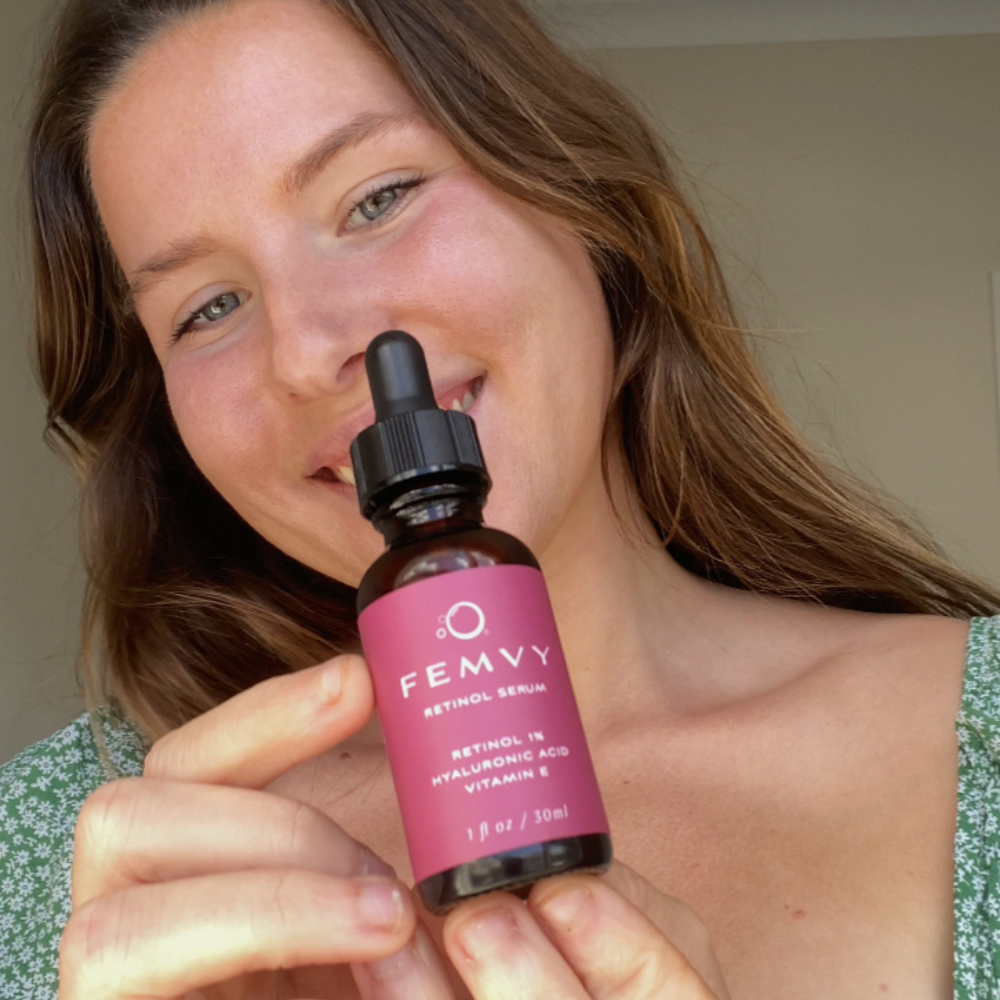 a woman showing a bottle of femvy retinol serum